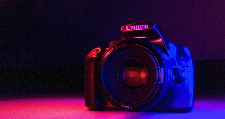 a digital camera sitting on top of a table, by Tom Carapic, unsplash contest winner, art photography, blue and red lights, purple filter, canon eos digital rebel xti, glowing with colored light