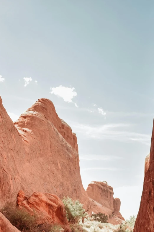 a man riding a motorcycle down a dirt road, inspired by Wes Anderson, trending on unsplash, visual art, tall stone spires, red sandstone natural sculptures, minimalist photo, white sweeping arches