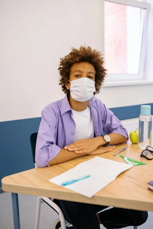 a woman sitting at a desk wearing a face mask, a picture, black teenage boy, isaac zuren, healthcare, boys