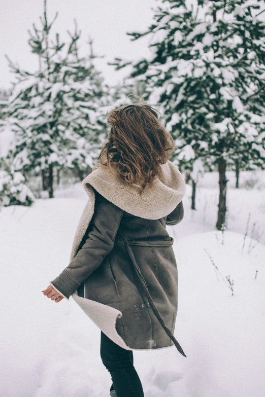 a woman standing in the snow with her back to the camera, trending on pexels, coat, date, flowy, brunette