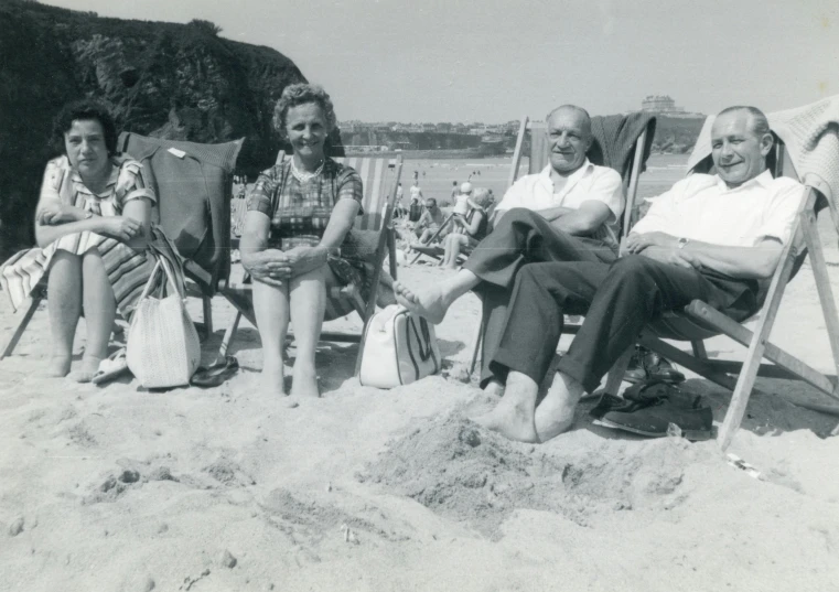 a group of people sitting on top of a sandy beach, a black and white photo, by Ruth Collet, pexels, naive art, in a sun lounger, dean cornwall, smug look, old chairs