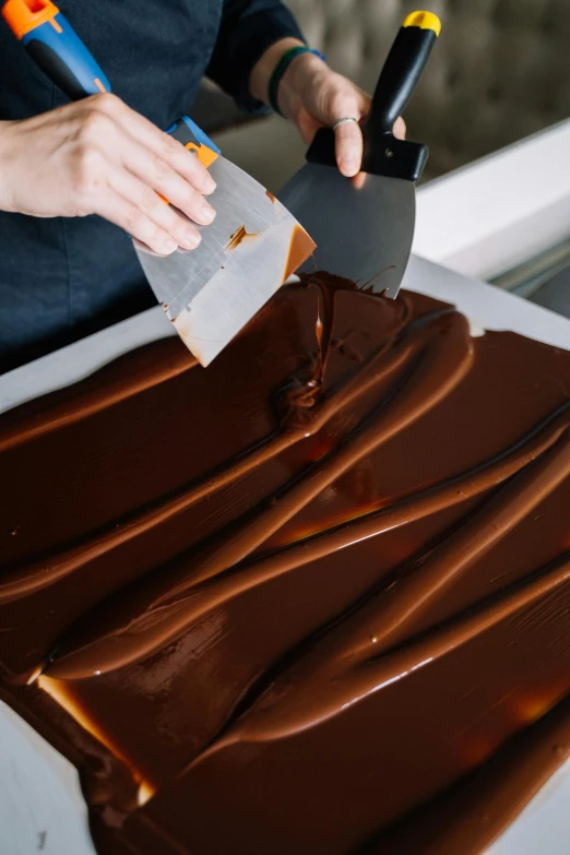 a person cutting a piece of chocolate with a knife, caramel, sleek flowing shapes, highly upvoted, sydney