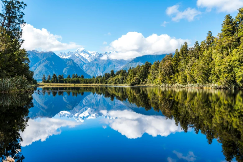 a body of water surrounded by trees and mountains, new zealand, mirrors, avatar image, travel guide