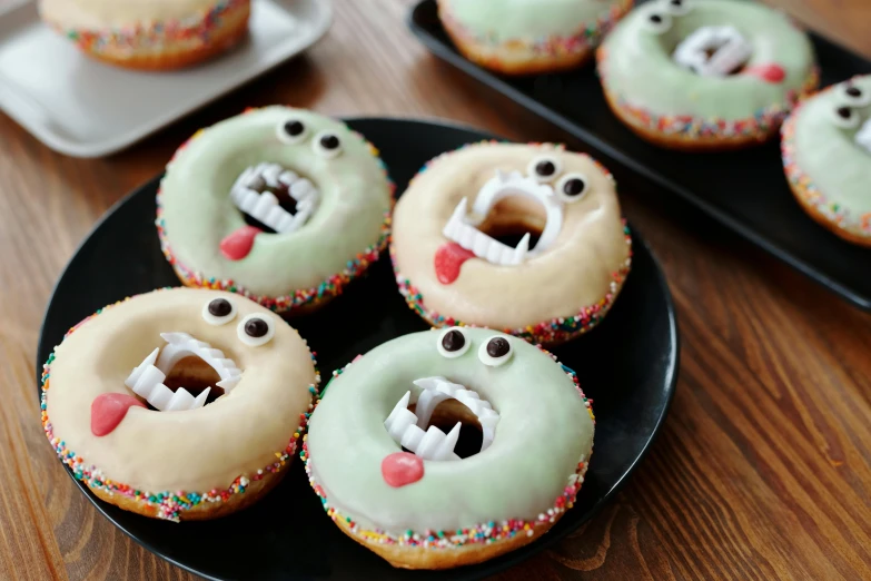 a black plate topped with donuts covered in frosting, by Murakami, trending on pexels, hurufiyya, gelatinous with teeth, large fangs, 2 years old, bakery