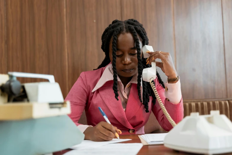 a woman sitting at a desk talking on a phone, by Lee Loughridge, pexels contest winner, lupita nyong'o, writing on a clipboard, wearing headmistress uniform, brown and pink color scheme