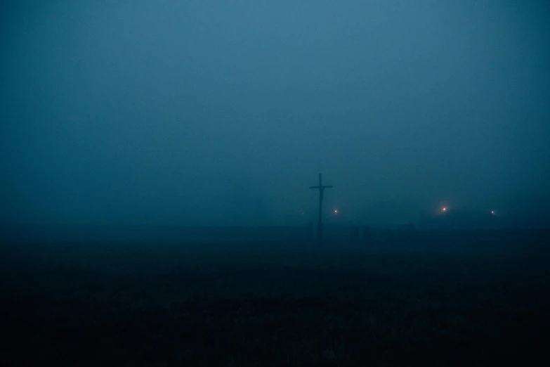 a cross in the middle of a foggy field, by Attila Meszlenyi, postminimalism, moody blue lighting, southern gothic scene, dark, exorcist