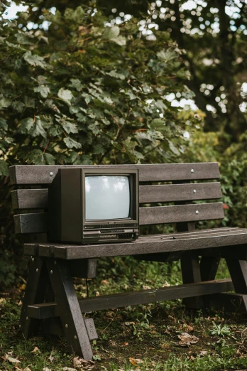 an old television sitting on top of a wooden bench, unsplash, video art, sitting on a park bench, commodore 6 4, 1990s photograph, alex heywood