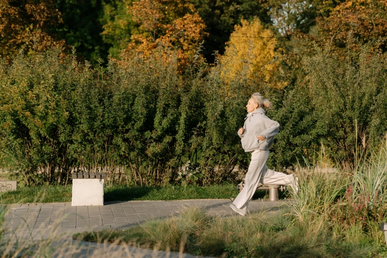 a woman running in a park with trees in the background, by Emma Andijewska, happening, bench, marina federovna, 7 0 years old, thumbnail