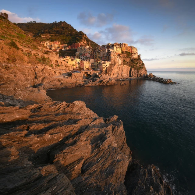 a cliff in the middle of a body of water, by Carlo Martini, pexels contest winner, renaissance, cinq terre, sunny morning light, multi - coloured, brown