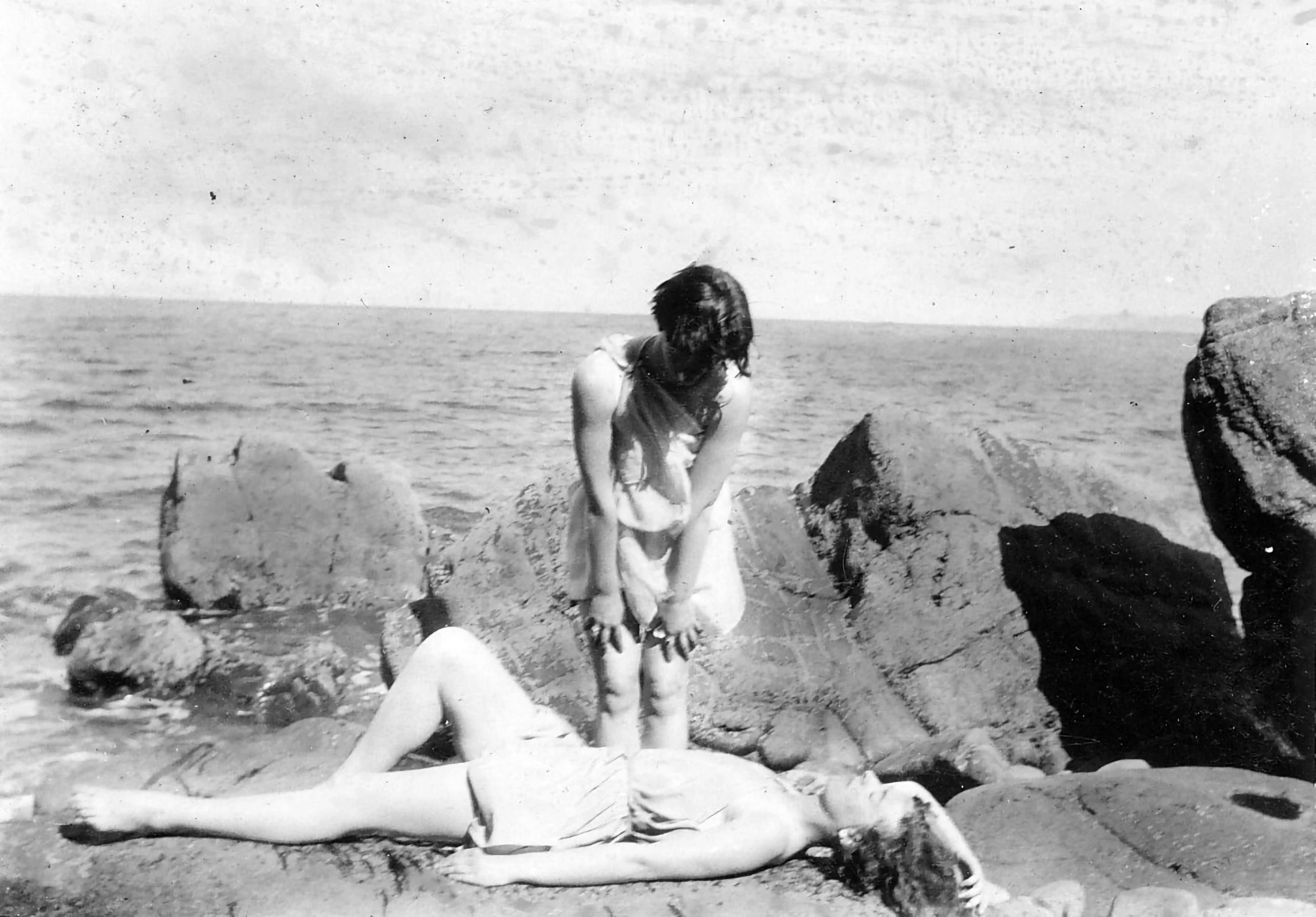 a couple of women laying on top of a rocky beach, by Edward Corbett, tumblr, surrealism, 1930s photograph, lesbians, demonic photograph, pale