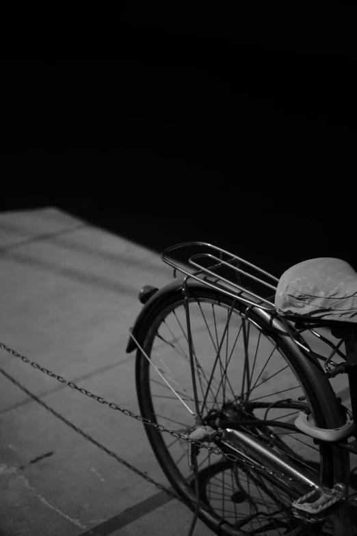 a black and white photo of a bicycle parked on a sidewalk, by Andrew Domachowski, in the moonlight, from yowamushi pedal, ( ( ( in a dark, back - shot