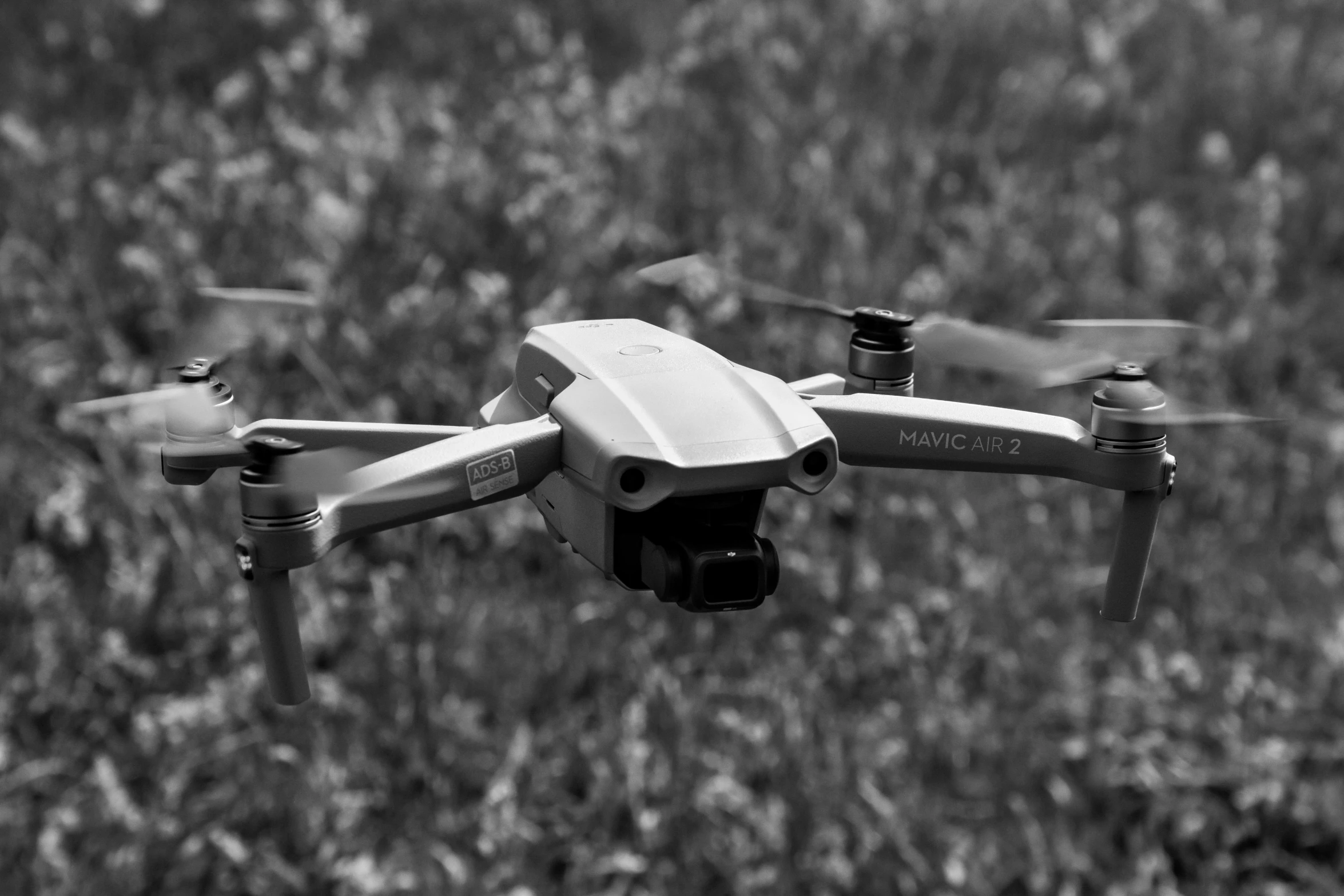 a black and white photo of a quadcopter flying over a field, by Carey Morris, pexels, vines, iridescent technology and weapon, 🦑 design, a green