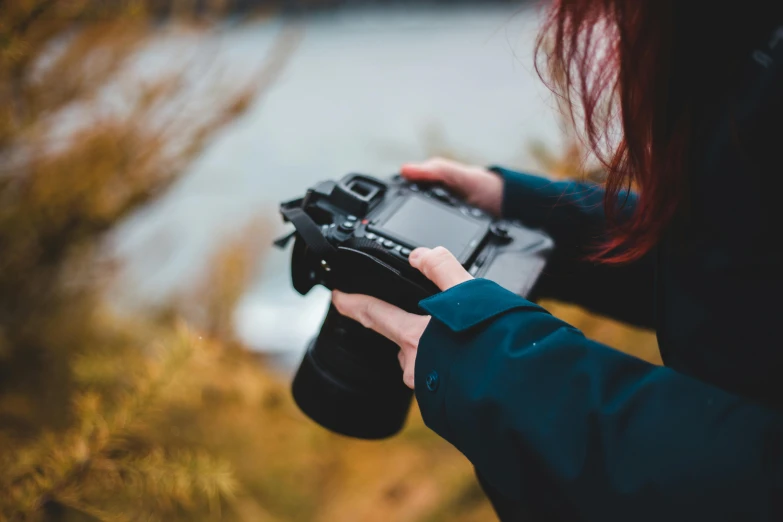 a person holding a camera near a body of water, by Carey Morris, pexels contest winner, hasselblad film bokeh, camera looking up at her, low colour, instagram post