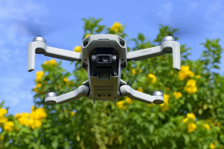 a close up of a camera attached to a drone, by Carey Morris, pexels, plein air, with yellow flowers around it, summer sky, slide show, exterior shot