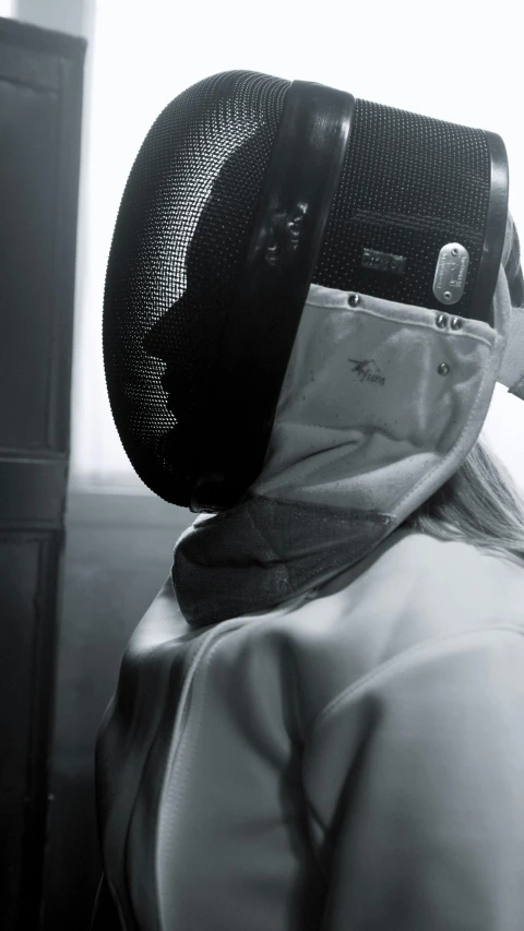 a black and white photo of a fencer wearing a mask, an album cover, unsplash contest winner, futuristic female beekeeper, ilse gort, hooded, tournament