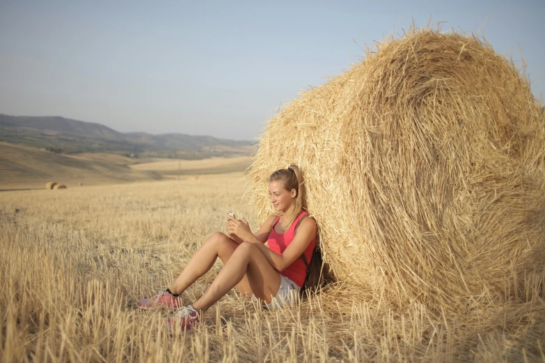 a woman sitting in a field next to a bale of hay, pexels contest winner, avatar image, spaghetti, field notes, without text