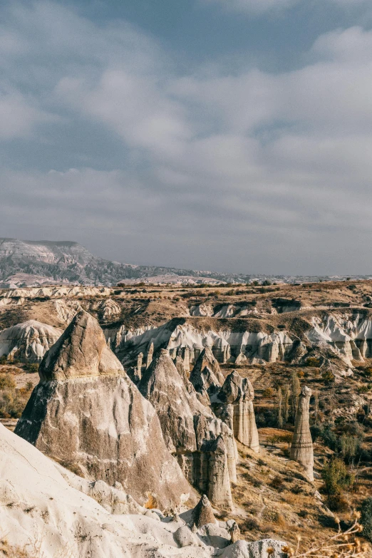 a man standing on top of a rock formation, trending on unsplash, art nouveau, black domes and spires, turkey, panorama distant view, white travertine terraces