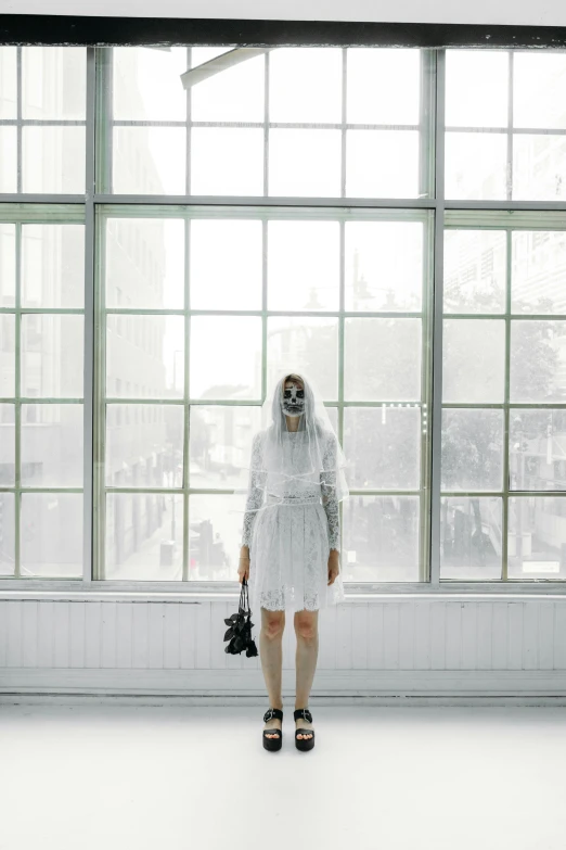 a woman in a white dress standing in front of a window, an album cover, inspired by Elsa Bleda, aestheticism, robot ghost mask, mall goth, white shoes, skeleton