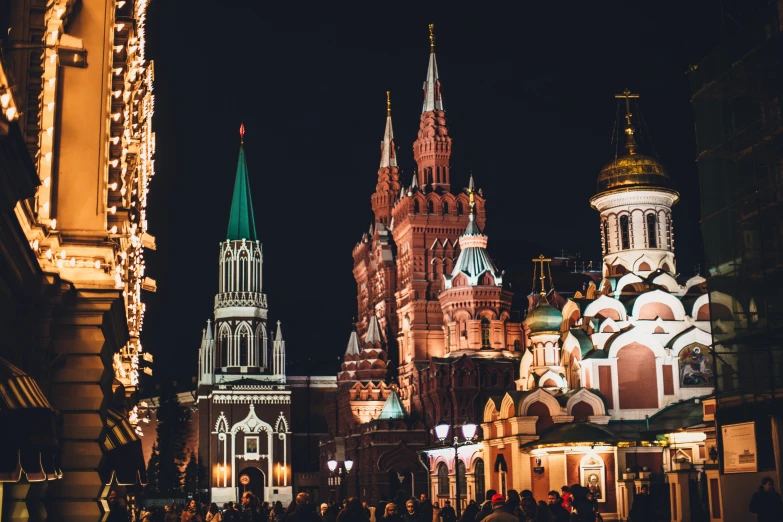 a group of people walking down a street next to tall buildings, by Julia Pishtar, pexels contest winner, baroque, red square moscow, festival. scenic view at night, spines and towers, square