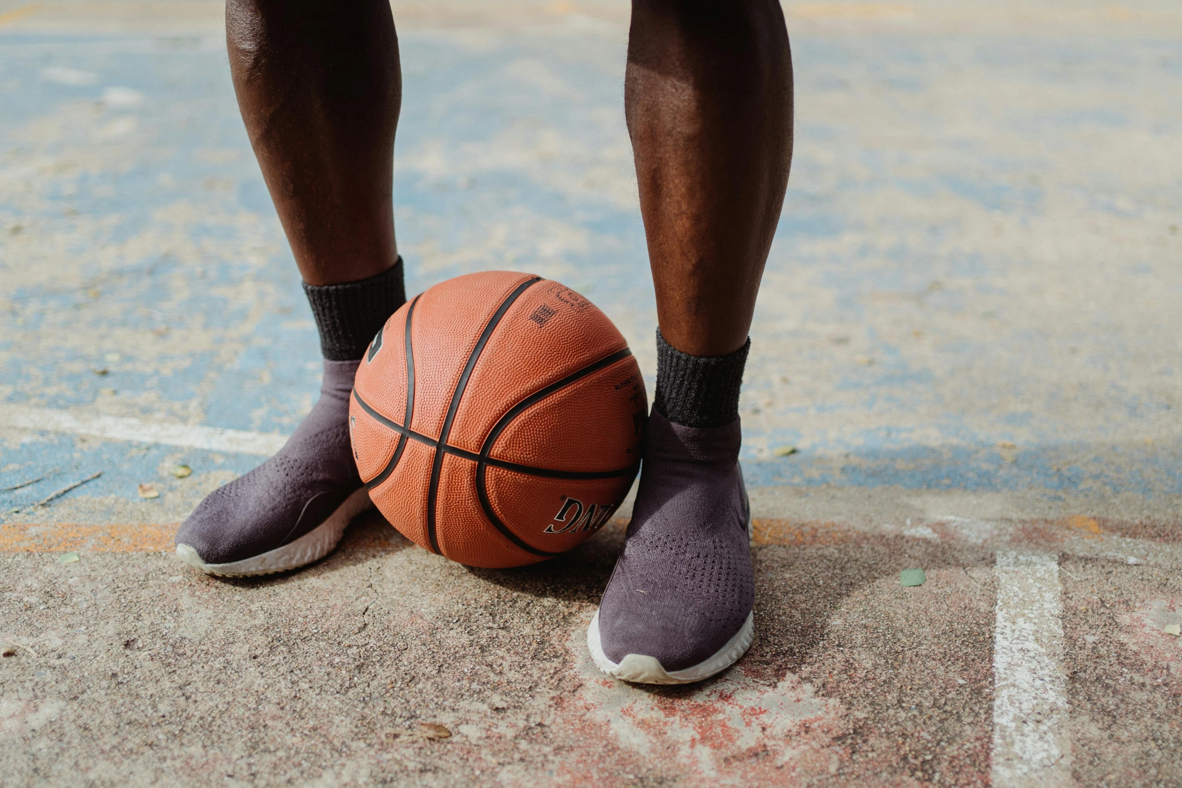 a man standing next to a basketball ball on a court, by Carey Morris, trending on dribble, wearing kneesocks, solid grey, rubber waffle outsole, ( ( dark skin ) )