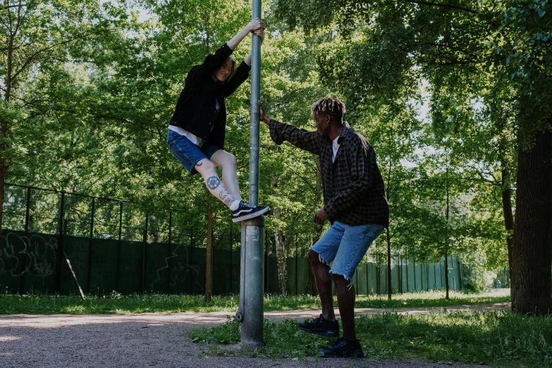 a man standing on top of a pole next to a woman, xxxtentacion, at a park, kickflip, supportive