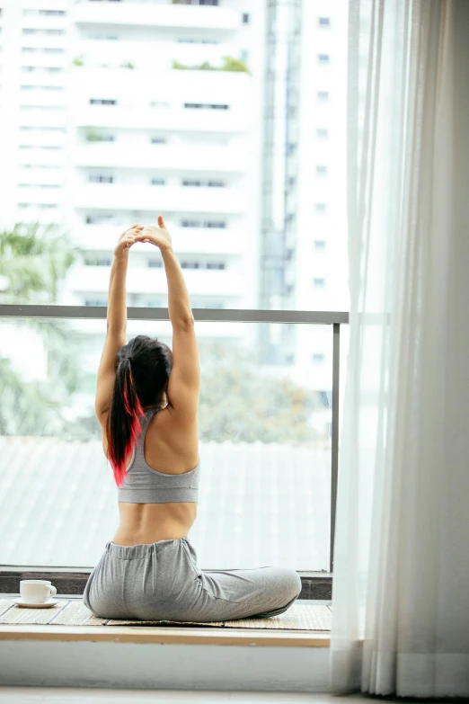 a woman sitting on a yoga mat in front of a window, pexels contest winner, arabesque, waist reaching ponytail, bangkok, square, arms out