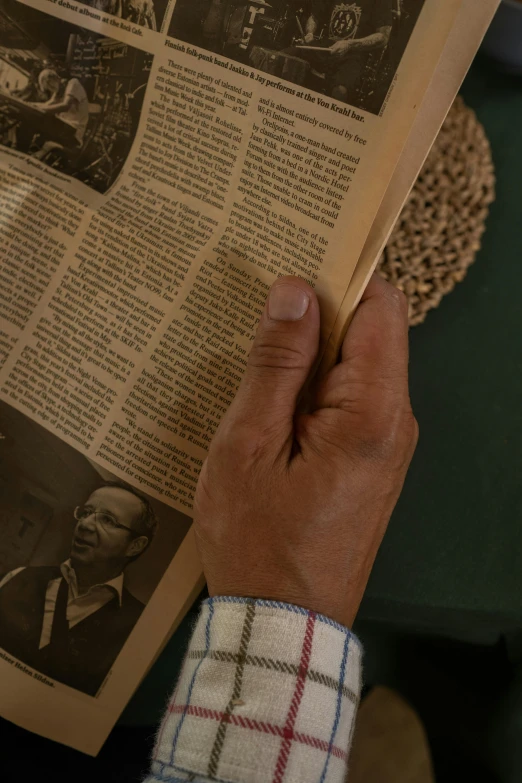 a person reading a newspaper on a table, photorealism, still frame the retro twin peaks, holding a wood piece, medium close - up ( mcu ), close-up from above