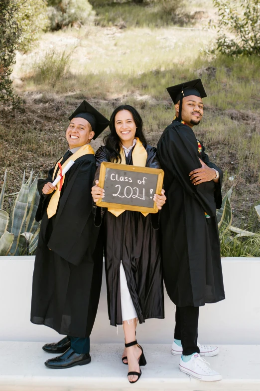 a group of people standing next to each other holding a sign, wearing an academic gown, 3 - piece, onyx, chalk