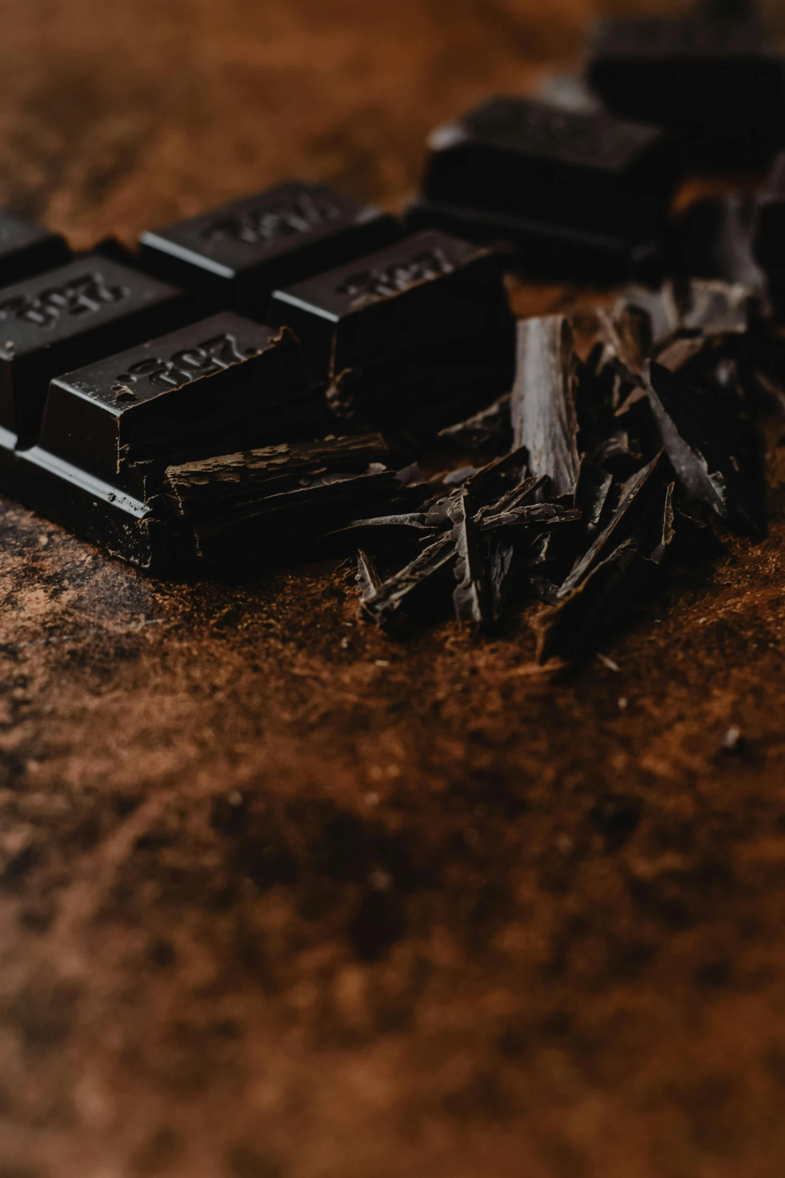 a piece of chocolate sitting on top of a wooden table, trending on pexels, black on black, ingredients on the table, bark, thumbnail