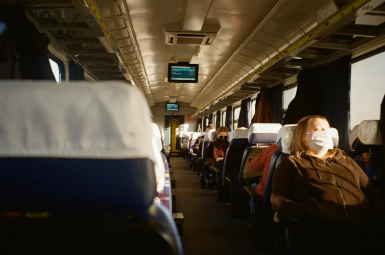 a woman wearing a face mask on a bus, by Carey Morris, pexels, sat down in train aile, avatar image, ultrawide cinematic, group photo