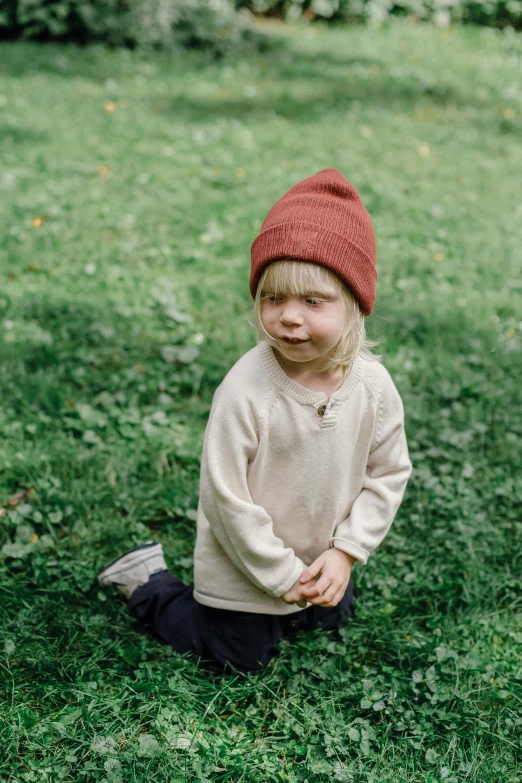 a little boy that is sitting in the grass, wearing a beanie, organic color, ember, thumbnail