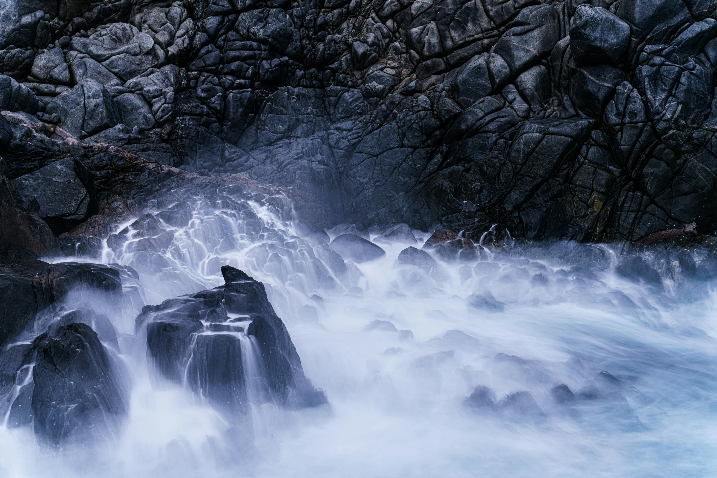 a bird sitting on some rocks in the water, an album cover, by Andrew Geddes, unsplash contest winner, australian tonalism, an eerie whirlpool, water mist, grotto, unsplash 4k