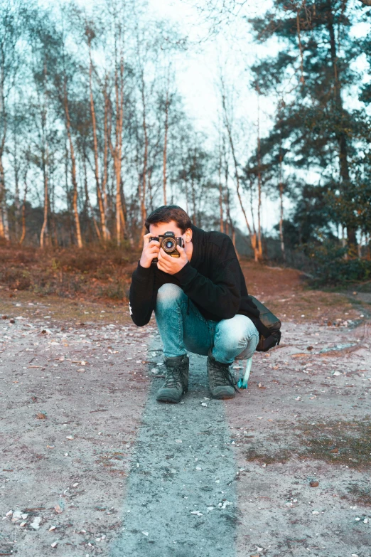 a man taking a picture of himself with a camera, a picture, by Jan Tengnagel, unsplash, art photography, crouching, in front of a forest background, shot with a camera flash, low quality photo