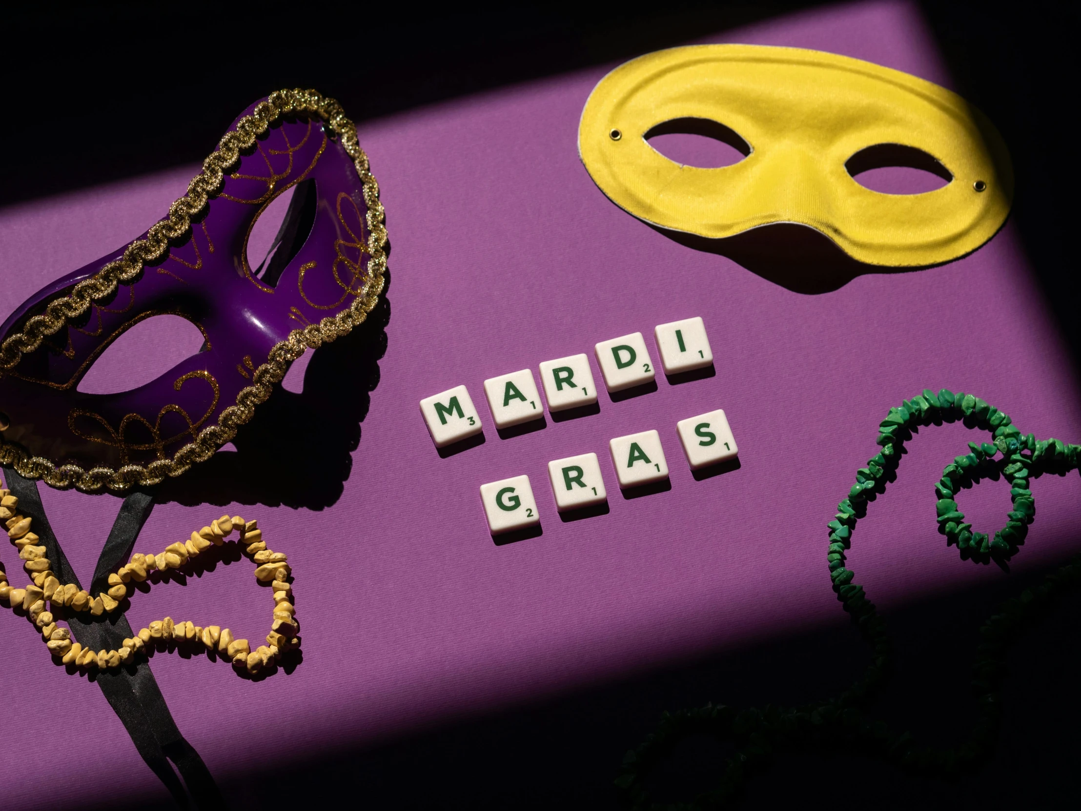 a couple of mardi gras masks sitting on top of a purple table, a portrait, trending on pexels, word, cubes on table, various artists, cutout