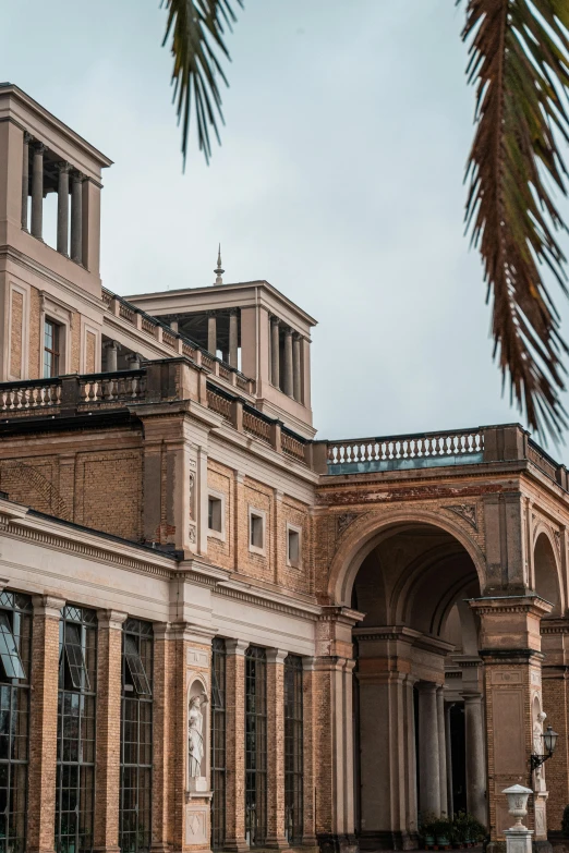 a large building with a palm tree in front of it, inspired by Frederick Goodall, neoclassicism, archways between stalagtites, museum photograph, buenos aires, 4k museum photograph