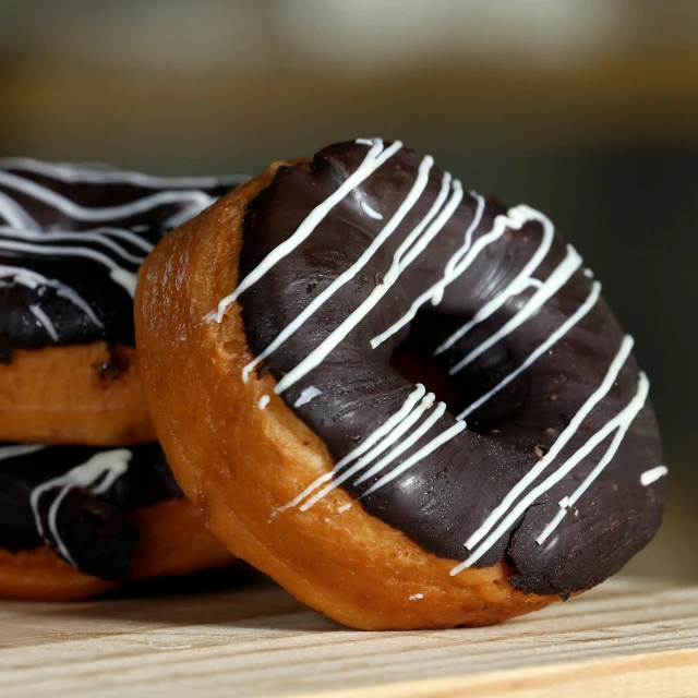 a couple of doughnuts sitting on top of a wooden table, profile image