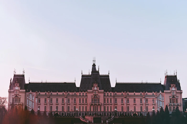 a large building sitting on top of a lush green field, inspired by Wes Anderson, pexels contest winner, baroque, pink sky, prague, front, government archive photograph