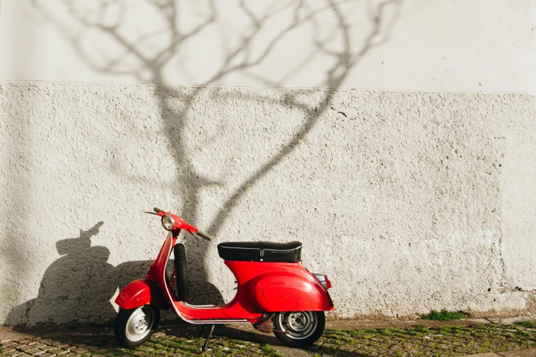 a red scooter parked next to a white wall, inspired by Peter de Sève, unsplash contest winner, under the soft shadow of a tree, back lit, conde nast traveler photo, shaped picture