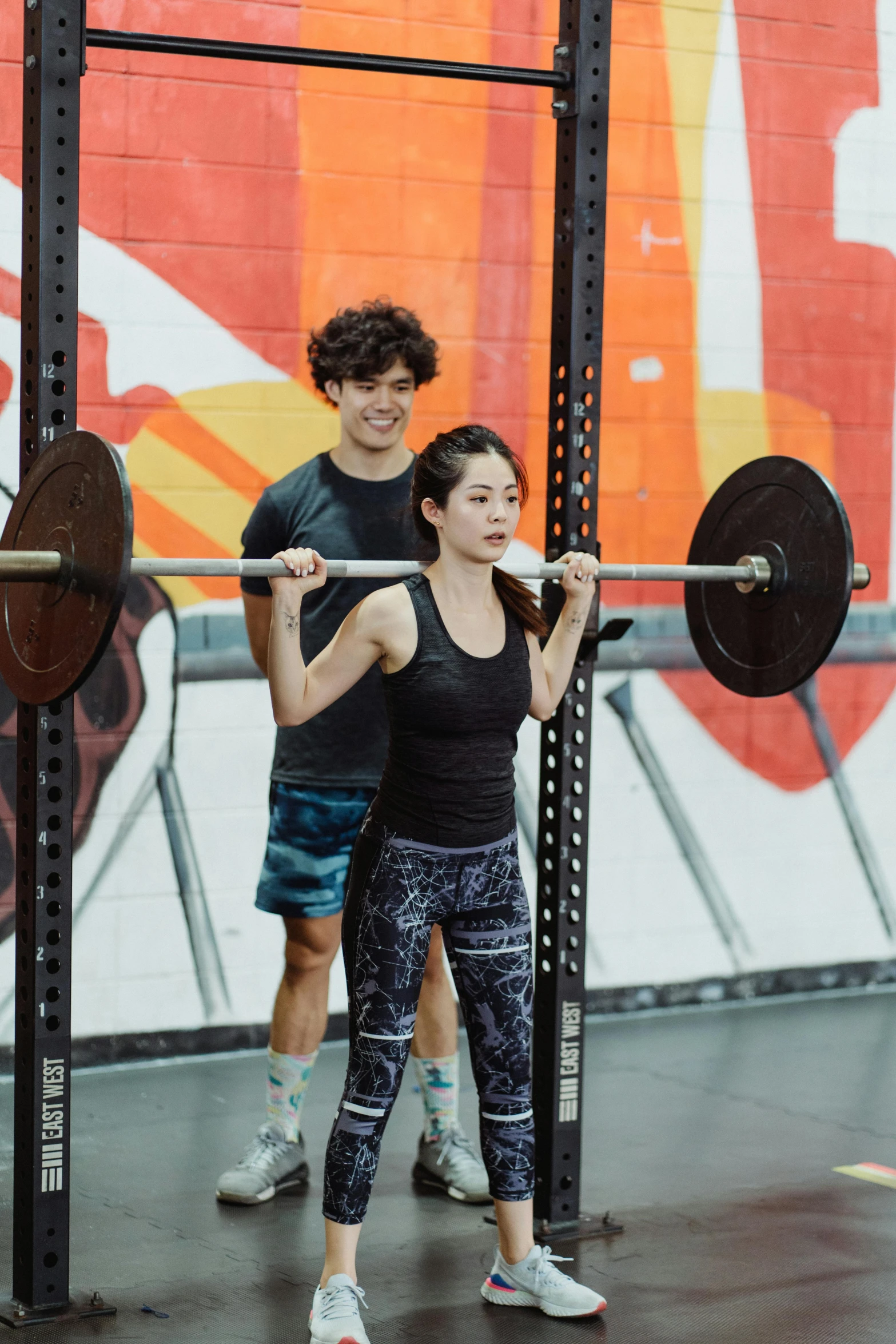 a man and a woman doing squats with a barbell, by Arabella Rankin, gemma chen, square, yan morala, standing