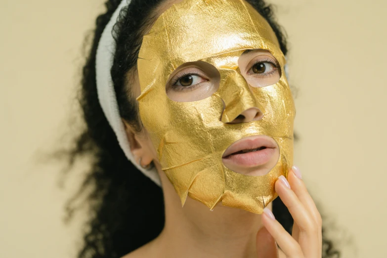 a woman with a gold mask on her face, trending on pexels, manuka, clear [bronze] face, cardboard, bark for skin