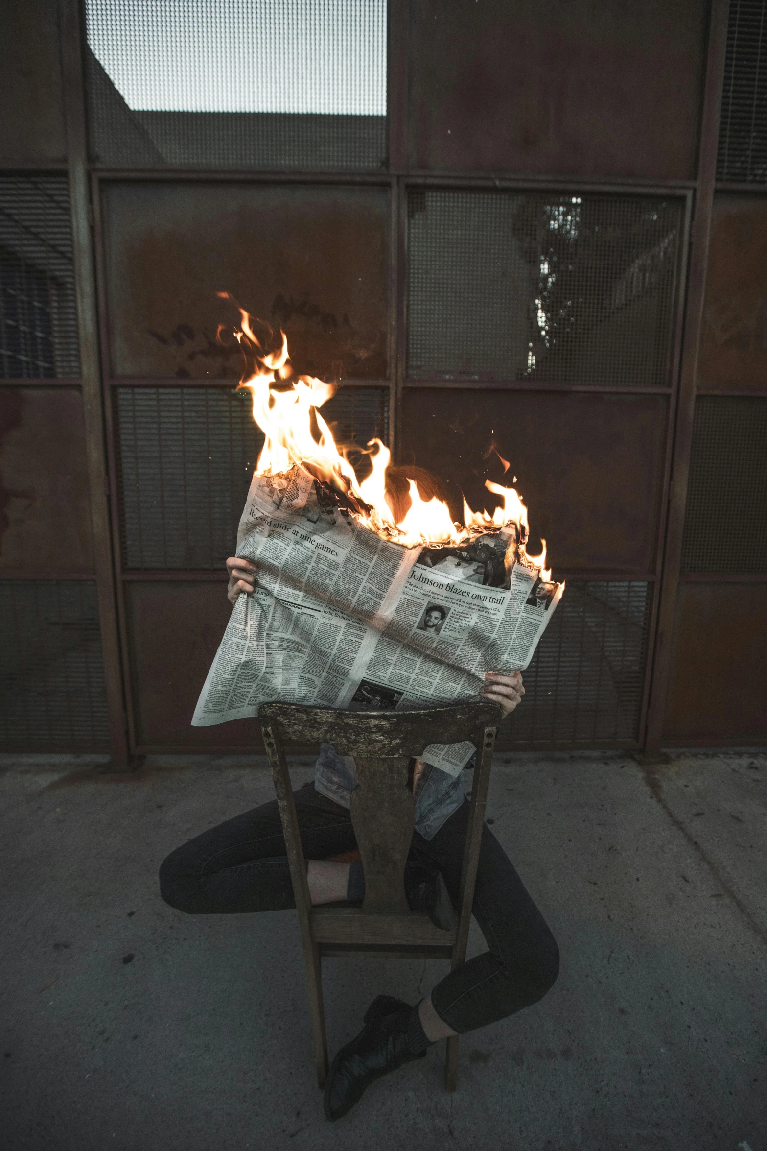 a person sitting on a chair with a newspaper on fire, an album cover, unsplash, renaissance, annie liebowitz, building on fire, contorted, hollywood standard