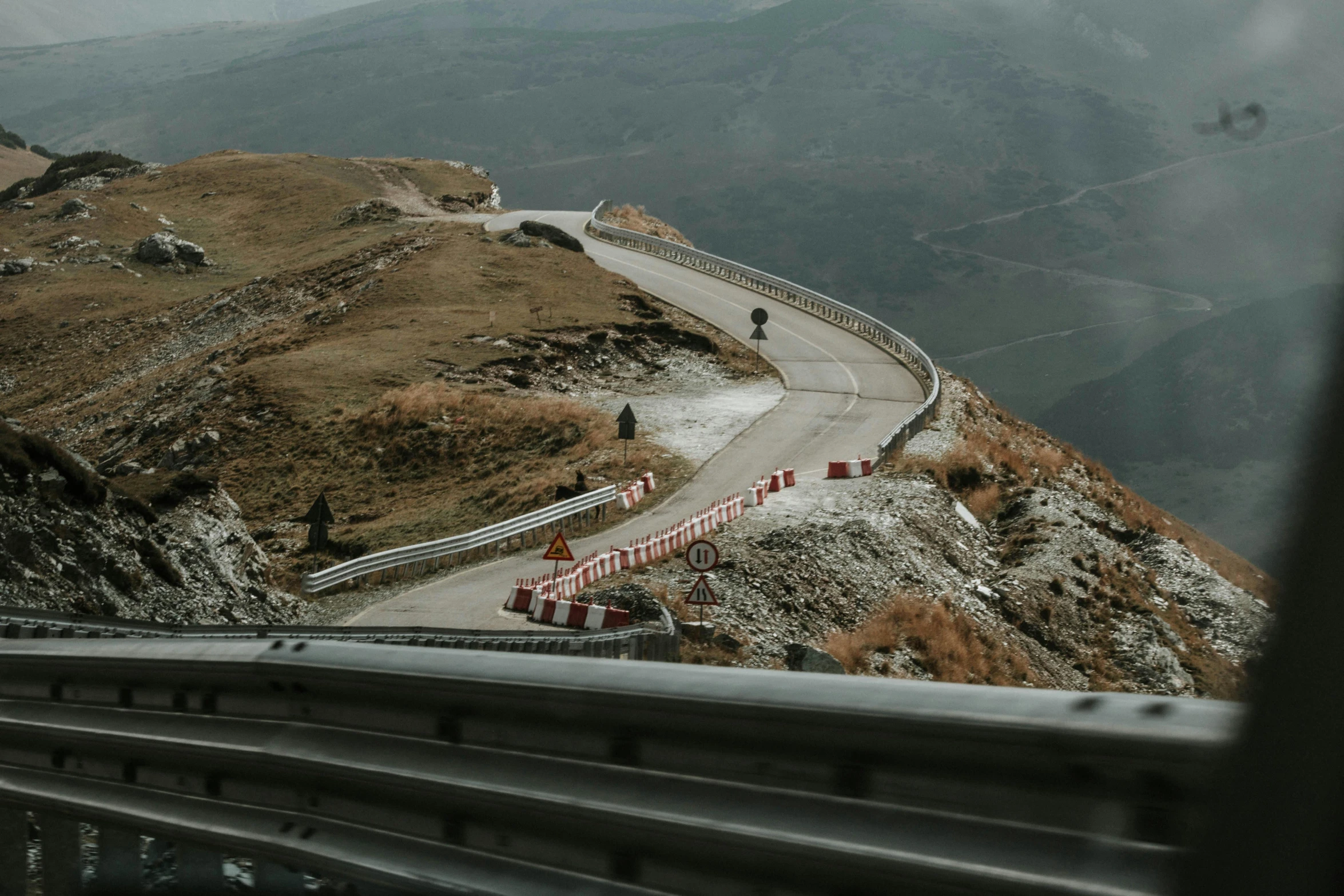 a person riding a motorcycle down a winding road, by Alessandro Allori, pexels contest winner, les nabis, guardrail, on top of a mountain, construction, slightly pixelated