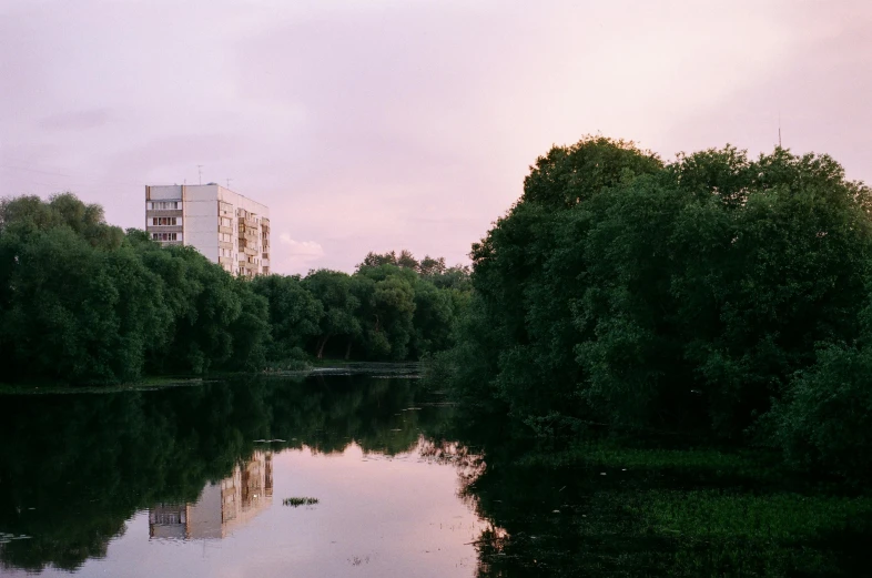 a body of water surrounded by trees and buildings, by Attila Meszlenyi, unsplash, hurufiyya, medium format. soft light, pink sky, nikolay georgiev, government archive photograph