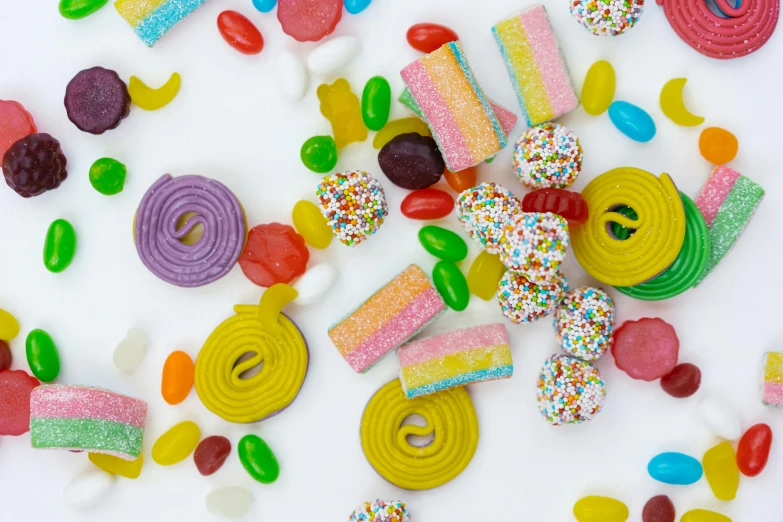 a table topped with lots of different types of candies, trending on pexels, with a white background, background image, gummy worms, flatlay