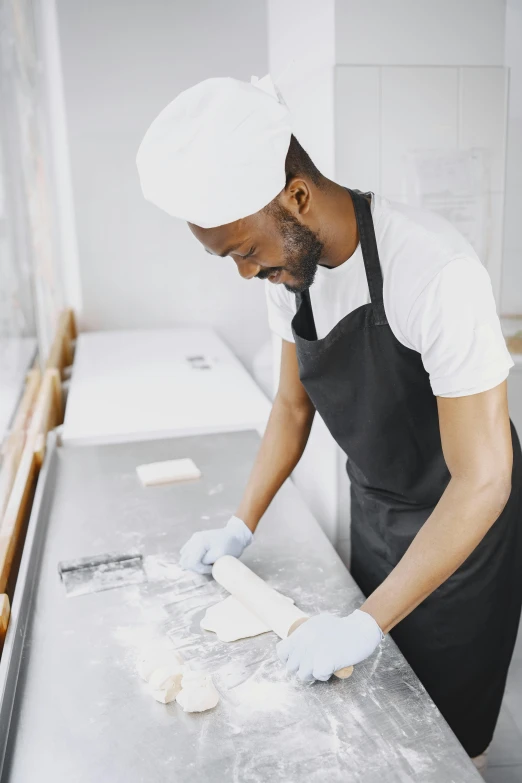 a man in an apron kneads dough on a counter, a silk screen, inspired by Barthélemy Menn, trending on unsplash, black man, thumbnail, profile pic, architect