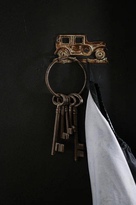 a bunch of keys hanging from a hook, steampunk car, detailed product image, on a black wall, small