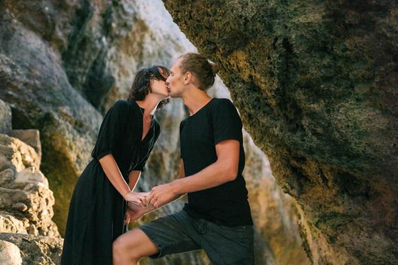 a man and a woman kissing on the beach, pexels contest winner, natural cave wall, manuka, black, basil gogos