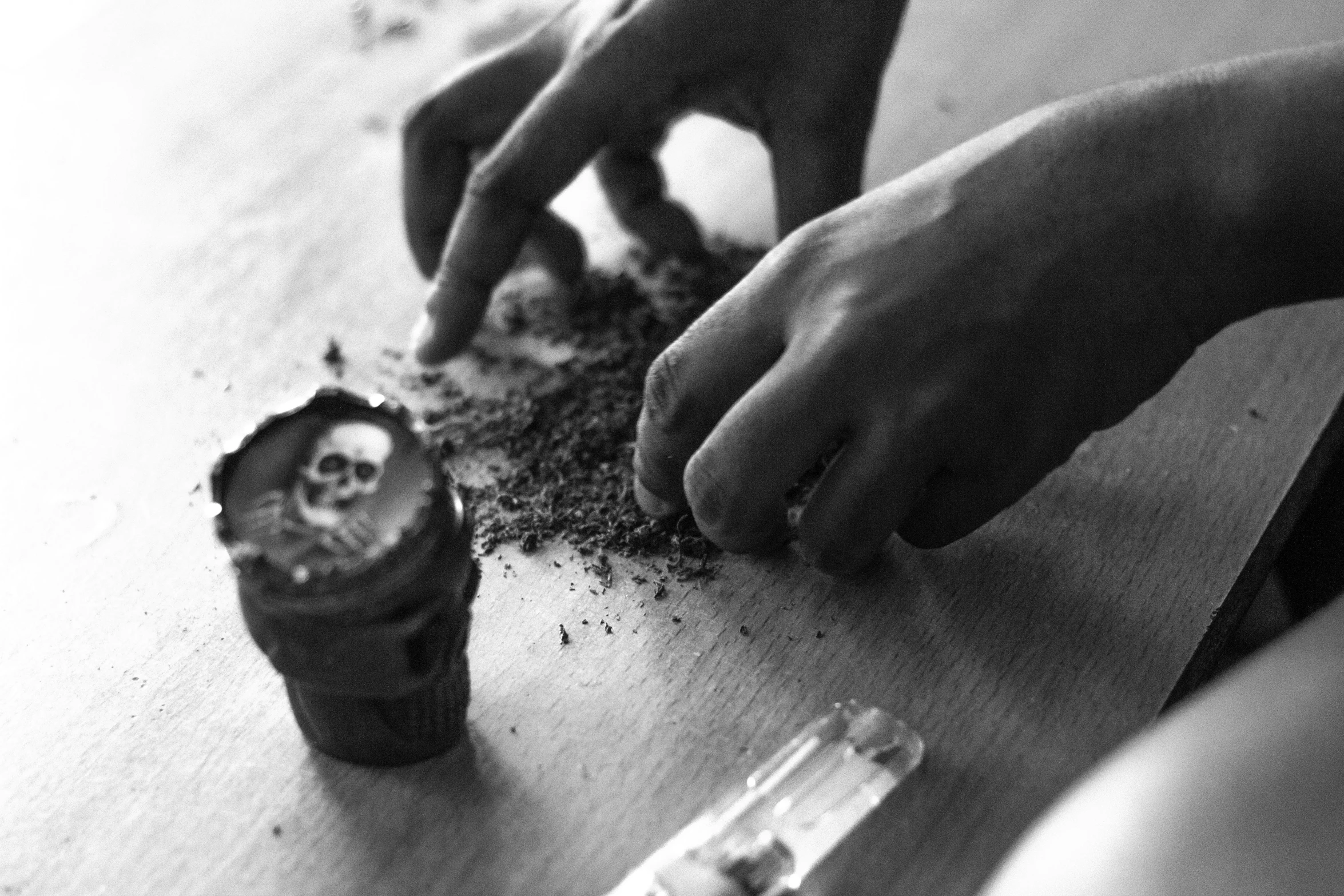 a black and white photo of a person making a cupcake, by Santiago Martínez Delgado, vanitas, taking tobacco snuff, psychedelic dust, close up shot of an amulet, there is a skull over a table