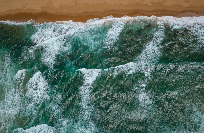 a large body of water next to a sandy beach, pexels contest winner, realism, turbulent sea, top - down photograph, wall of water either side, 4 k hd wallpapear