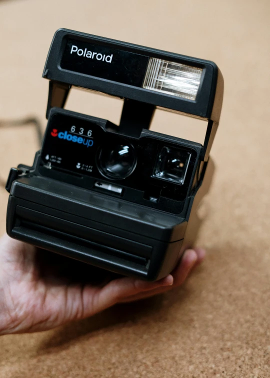 a person holding a polaroid camera in their hand, inspired by Nan Goldin, photorealism, photograph credit: ap, a portrait of an android, soft lighting sold at an auction, polaroid 6 0 0